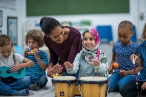 Little Muslim girl enjoy music class at school with her friends.